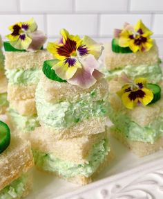 several pieces of cake with green frosting and flowers on them sitting on a white plate