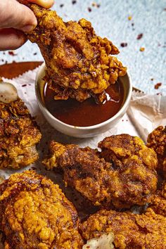 a person dipping sauce on some fried food