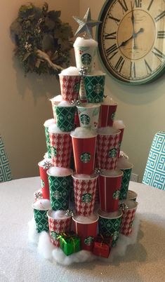 a christmas tree made out of cups on a table with a clock in the background