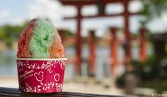 a cup filled with colorful powder on top of a wooden table next to a lake