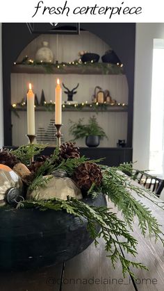 a bowl filled with pine cones and greenery on top of a wooden dining table