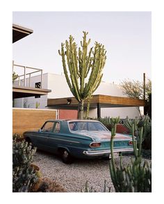 an old car is parked in front of a house with cactuses and cacti