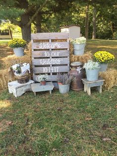 a sign that says welcome to our wedding surrounded by hay bales and flower pots