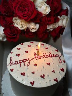 a white cake with red and white roses on it next to a bouquet of flowers