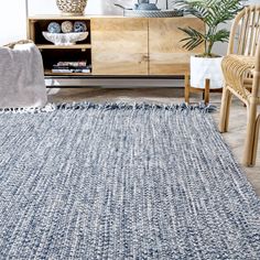 a blue rug in a living room next to a wooden cabinet and wicker chair