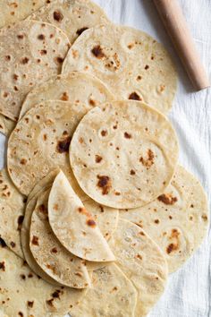 several tortillas are stacked on top of each other with a rolling pin in the background