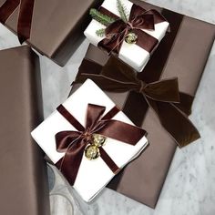 three wrapped presents are sitting on a marble counter top with ribbons and bows around them