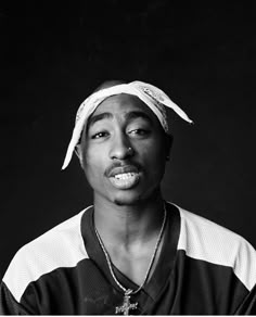 a black and white photo of a man with a hat on holding a cell phone