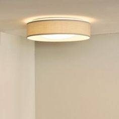 a round light fixture mounted on the side of a wall in a room with white walls