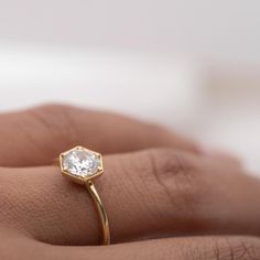 a woman's hand with a gold ring on it and a diamond in the middle