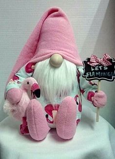 a pink stuffed gnome with a sign that says let's flamingo