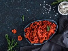 a bowl filled with dried carrots next to some herbs