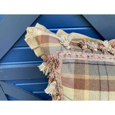 a plaid pillow with tassels on it sitting in front of a blue wall