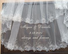 the wedding veil is hanging on top of the wooden door with white flowers and leaves