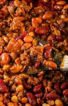 beans and meat are being stirred with a wooden spoon