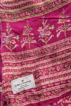 the label is on an old pink and green cloth with floral designs, which has been worn