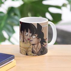 a dragon and gohan mug sitting on top of a table next to a book