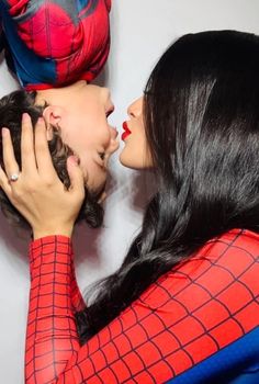 two women kissing each other in front of a spider man