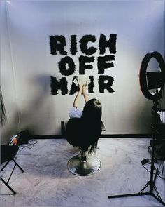 a woman sitting on top of a chair in front of a wall with the words, rich off hair