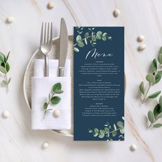 a menu card on a plate with silverware next to it and green leafy napkins