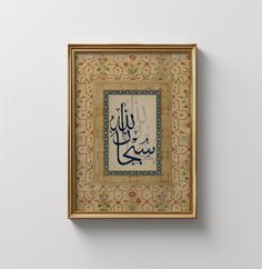 an arabic calligraphy is displayed in a gold frame on a white wall with floral designs