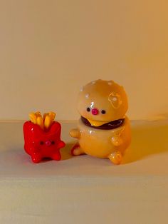 a yellow toy bear sitting next to a red object