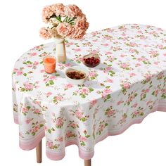 a white table topped with pink flowers and bowls of food next to a vase filled with roses