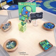 the earth book is on display in front of some bowls with beads and other items