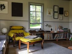 a living room filled with furniture and bookshelves next to a window covered in pictures