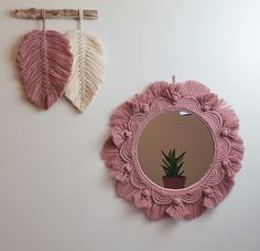 two mirrors hanging on the wall next to each other, one with a plant in it