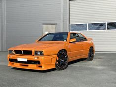 an orange car parked in front of a building