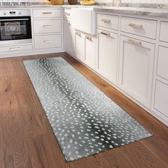 a kitchen with wooden floors and white cabinets, an oven and counter tops is seen in this image