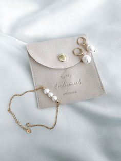 a card case with pearls on it sitting on top of a white bed sheet next to a chain