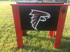 a black and red sign with the atlanta falcons logo on it sitting in some grass