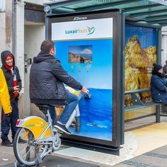 a man riding a bike next to a bus stop