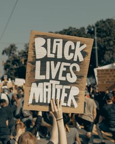 a person holding up a sign that says black lives matter in front of a crowd