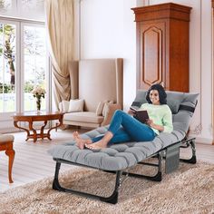 a woman sitting on a chaise lounge chair reading a book in a living room