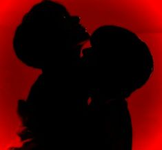 the silhouette of two people kissing in front of a red background