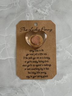 a tag with a penny in it on top of a marble countertop next to a bottle opener