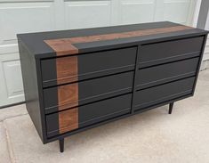 a black and brown dresser sitting on top of a cement floor next to a garage door