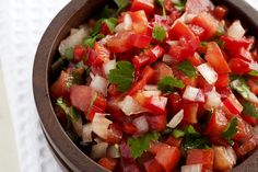 a wooden bowl filled with diced tomatoes and green onions on top of a white napkin