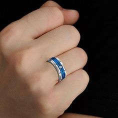 a man's hand wearing a blue and silver ring