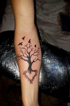 a tree with birds flying around it on someones left foot and the bottom part of their leg is black