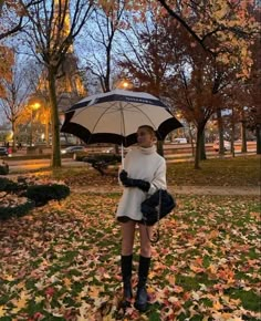 a woman is standing under an umbrella in the leaves