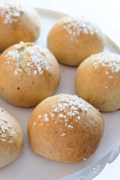 several rolls with white sprinkles sit on a plate