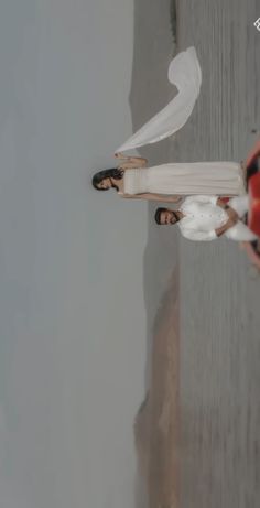 two people standing next to each other on the beach