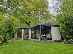 a small house sitting in the middle of a lush green field with lots of trees