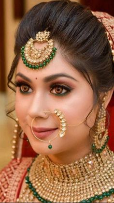 a woman with makeup and jewelry on her face, wearing an elaborate nose ring in gold