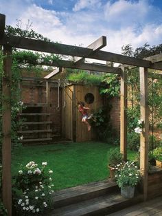 a backyard with a wooden pergoline and lots of greenery