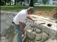 a man standing on top of a pile of rocks next to a stone wall with a hole in it